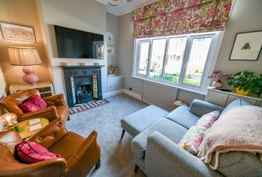 Image shows a lounge with a period cast iron fireplace, sofas and a modern television mounted on the wall, for the Property Sales page of the Jameson and Partners Altrincham Estate Agents website